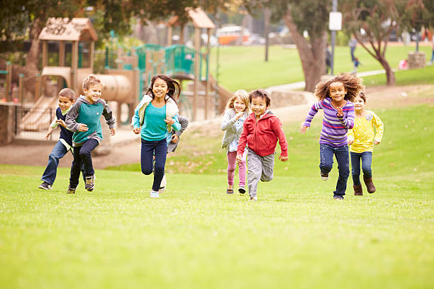 group of young children running towards camera in park smiling